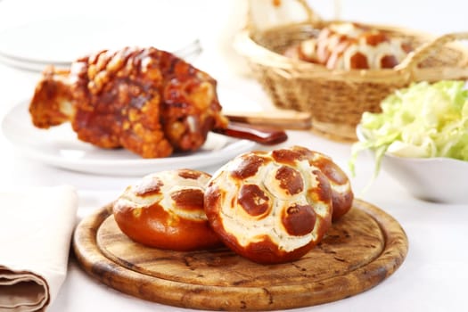 Rustic laugen rolls, traditional German pastry, with knuckle of pork and salad