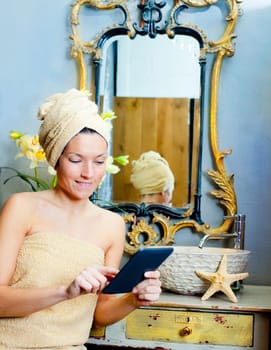 Female in bathroom reading ebook tablet relaxed