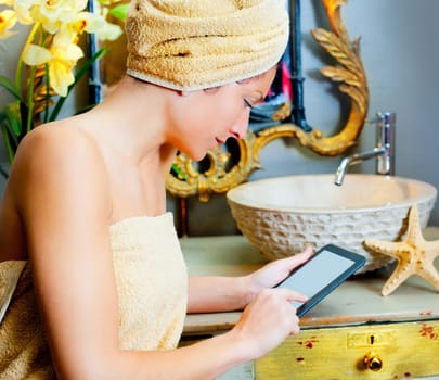Female in bathroom reading ebook tablet relaxed