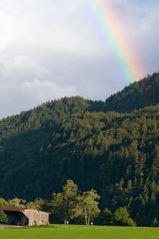 Rainbow at Lake Weissensee / Allgäu / Bavaria with mountain forest,green pasture and single barn