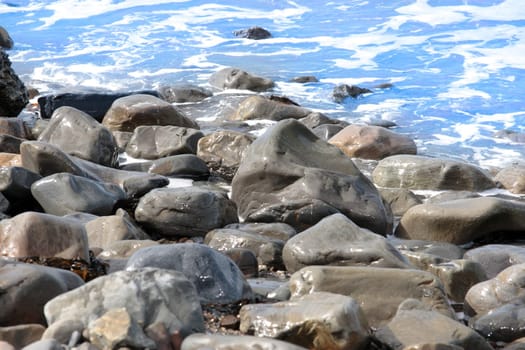 a pebbled beach on a warm day with a calm sea as a background