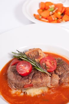 Ossobuco,braised veal shank slices with rosemary and tomatoes and tomato sauce and carrots as a side dish