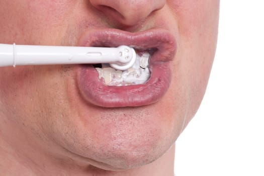 An electric toothbrush brushes a man's teeth