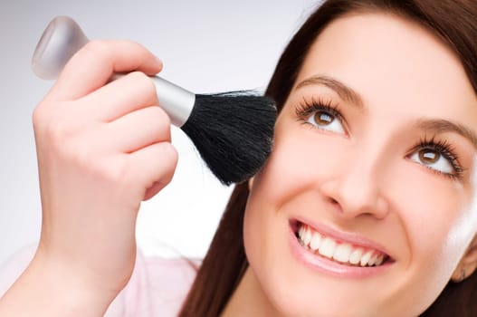 young pretty girl holding powder brush
