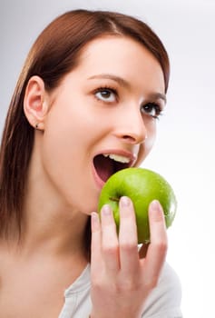 young brunette woman eating green apple close up