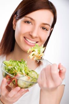 Young attractive woman eating salad close up