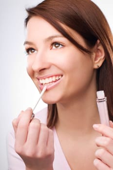 Young brunette woman applying lip gloss close up