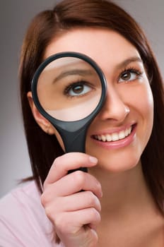 Young business woman looking through loupe close up