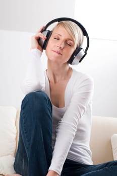 Young blond woman listening music on headphones
