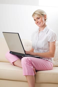 Young happy blond woman working on laptop