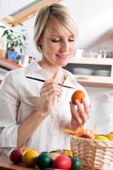 Young blond woman painting easter eggs close up