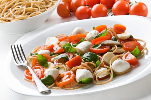 Sliced tomato and mozzarella with pasta close up