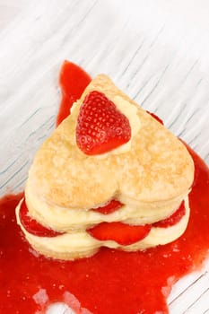 Heart shaped strawberries and custard millefeuille on strawberry sauce. For a sweet Valentine&#039 s Day. With copy-space Selective focus.