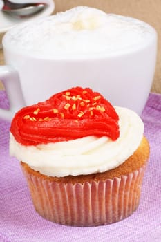 Fancy Valentine&#039 s day cupcake frosted with a red heart shape and a cappuccino.