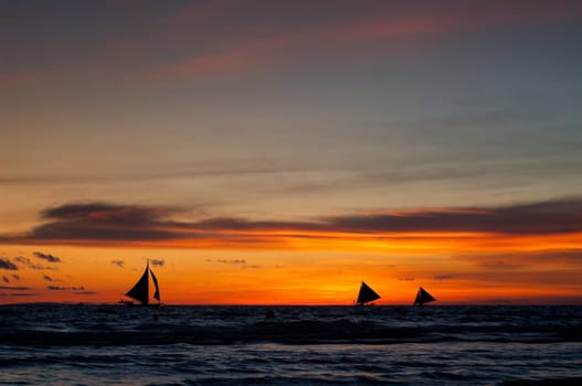 tropical beach with sailing boats at sunset
