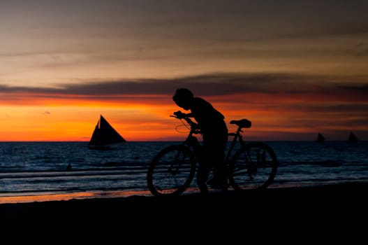 silhouette of a boy with a bicycle against a beautiful sunset
