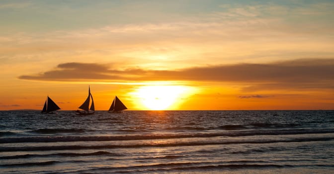 silhouettes of sailing boats against a colorful sunset