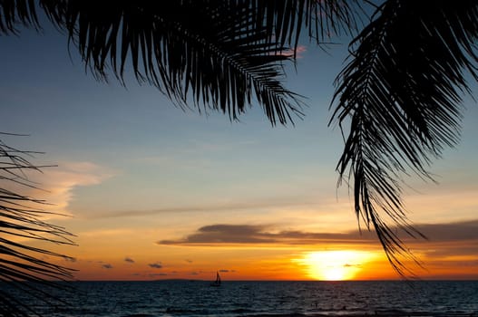 tropical beach with sailing boats at sunset