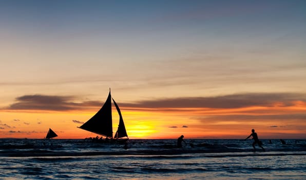 tropical beach with sailing boats at sunset