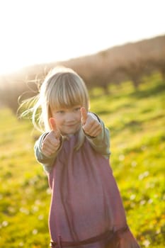 Cute little girl outdoors with thumbs up