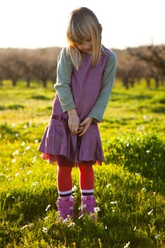 Cute little girl outdoors on a green field with flowers
