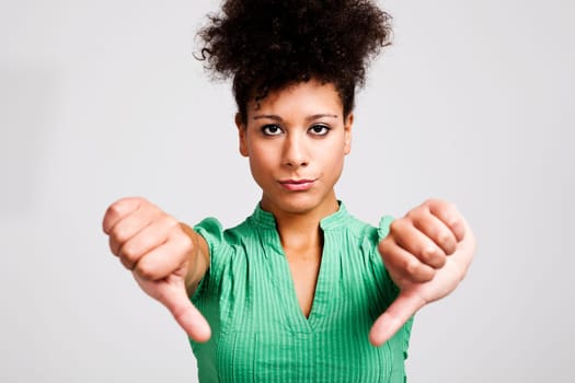 Beautiful woman with thumbs down. Studio shot.