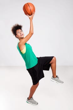 Athletic woman jumping with a basketball. Studio shot.