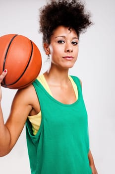 Athletic woman with a basketball on her shoulder. Studio shot.