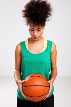 Athletic woman with a basketball in her hands. Studio shot.