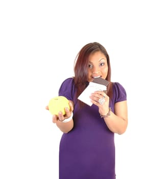 Young woman in a purple dress holding a yellow apple and a chocolate bare, liked the chocolate bar more, for white background.