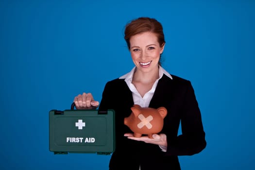 Young attractive businesswoman holding a piggybank with plasters on it as a money recovery concept.