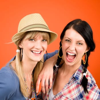 Two woman friends young crazy smile portrait on orange background