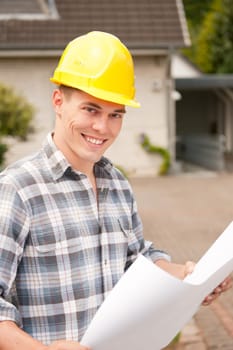 Young architect with a blueprint in front of a house