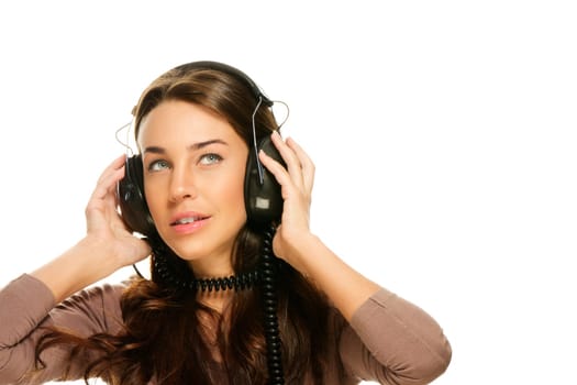 Young woman listening to music and looking up on white background