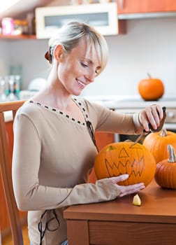 Young woman carving halloween pumpkin close up