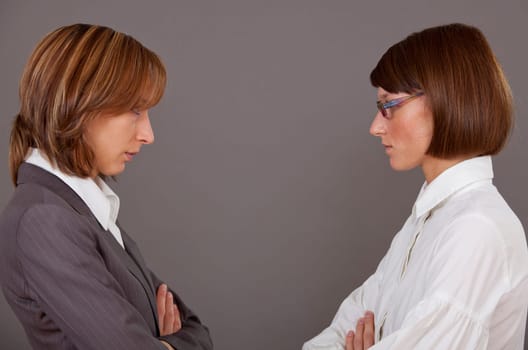 Two female business rivals in conflict over grey background