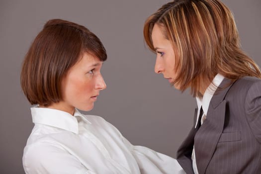 Two business women in conflict over grey background
