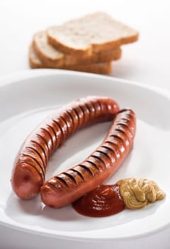 Grilled sausage with ketchup and mustard on white plate