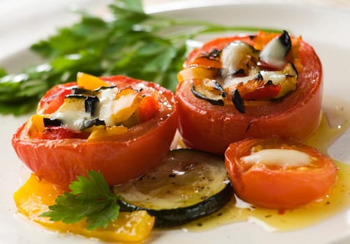 Baked tomatoes stuffed with wegetables and mozzarella cheese close up