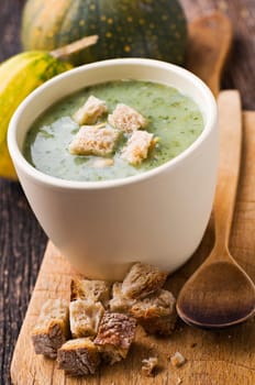 Fresh green pumpkin soup with bread close up