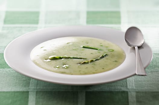 Fresh asparagus soup in white plate close up