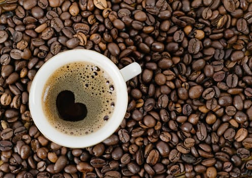 Background from coffee grains and a cup from coffee, the top view