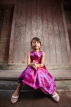 Portrait of cute Asian female child in pink dress looking at camera