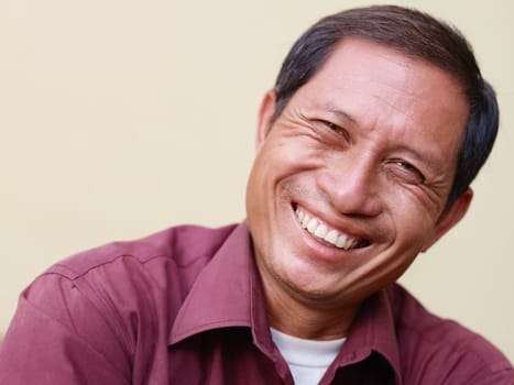 Portrait of happy mature Asian man smiling and looking at camera. Copy space