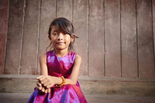 Portrait of cute Asian female child in pink dress looking at camera. Copy space