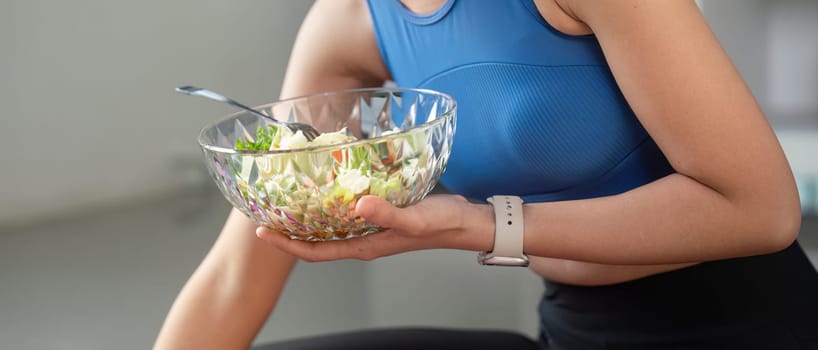 A dedicated woman mixes a colorful salad, promoting healthy eating and nutrition in a bright indoor setting.