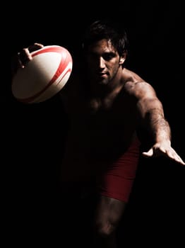 one caucasian sexy topless man scoring touchdown with  a rugby ball on studio black background
