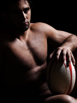 one caucasian sexy naked  man portrait holding rugby ball on studio black background