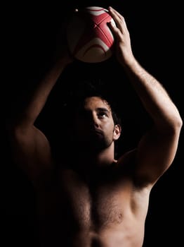 one caucasian sexy topless man portrait tossing a rugby ball on studio black background