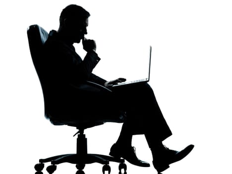 one caucasian business man computer computing serious sitting in armchair silhouette Full length in studio isolated on white background